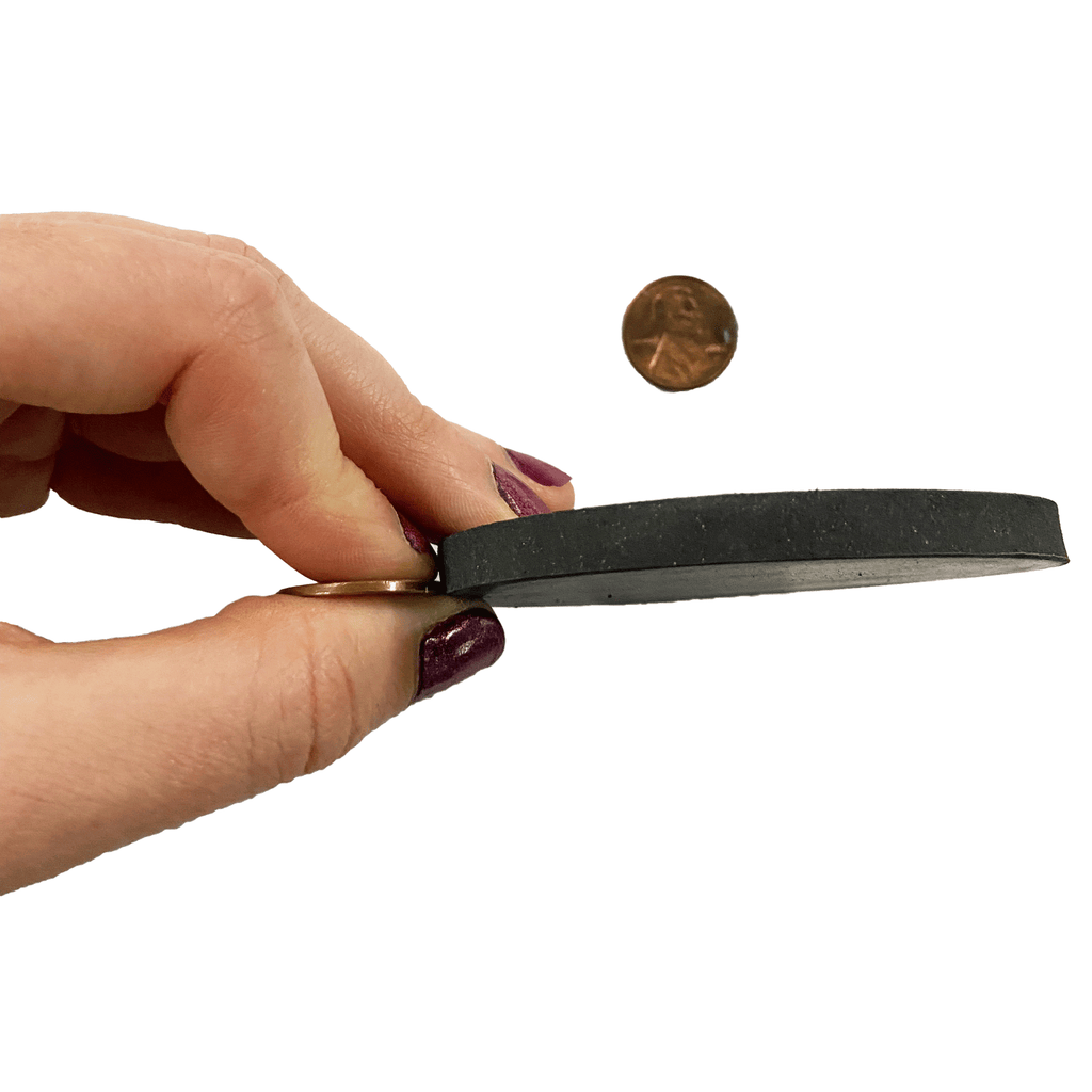 Quarter inch round rubber shim set being held up to a penny to show thickness