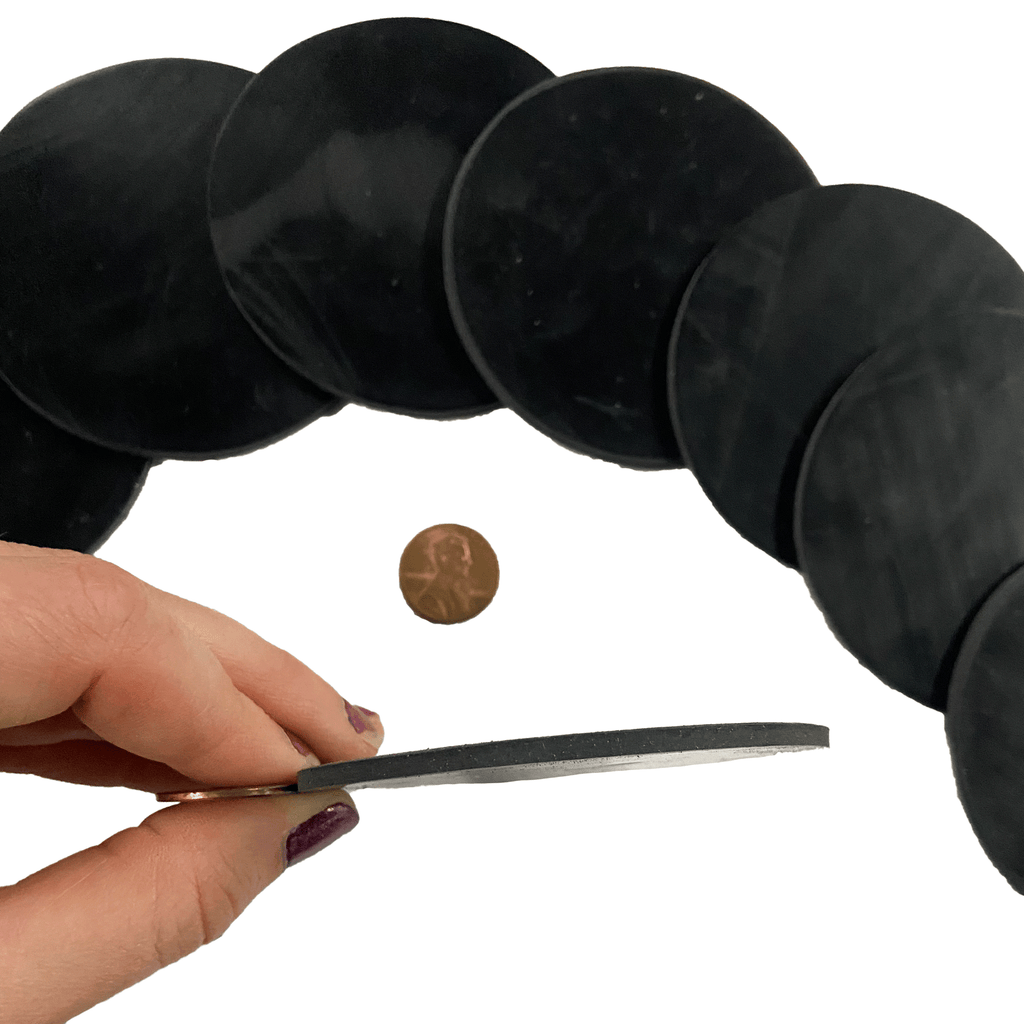 Eighth of an inch round rubber shim being held up to penny to compare thickness