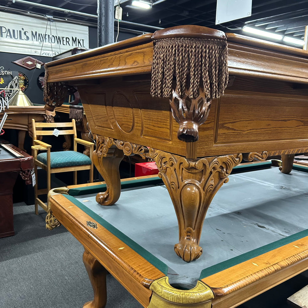 Corner view of oak pool table with fringe pocket and ram's head leg