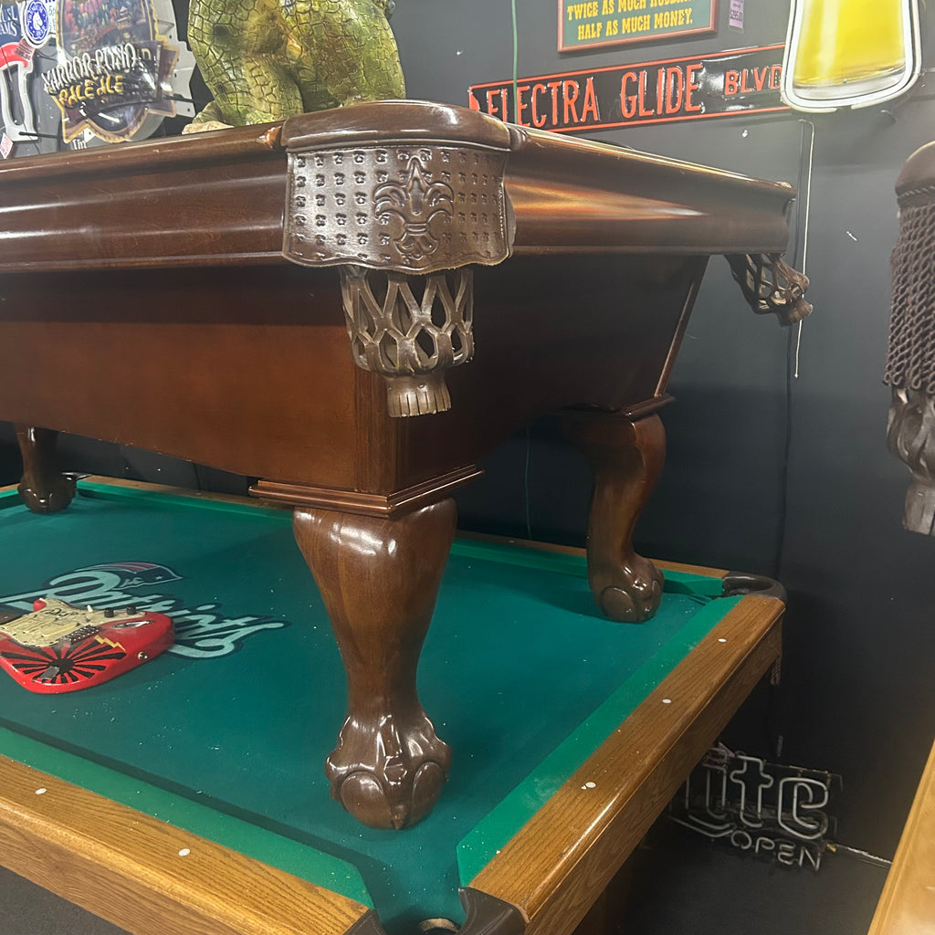 Corner view of pool table with walnut finish and leather shield pocket and ball and claw leg from right side