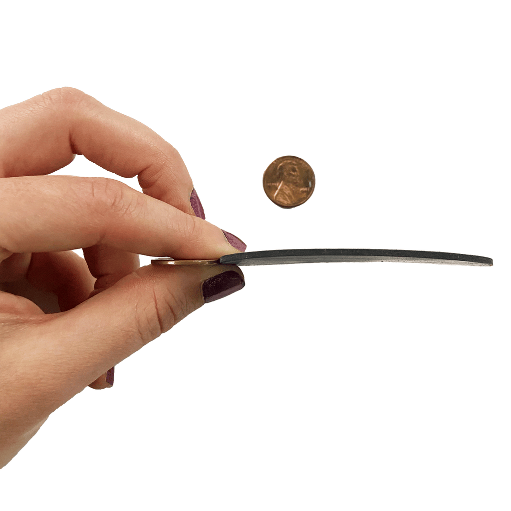 One sixteenth inch round rubber shim piece being held up to penny to compare thickness