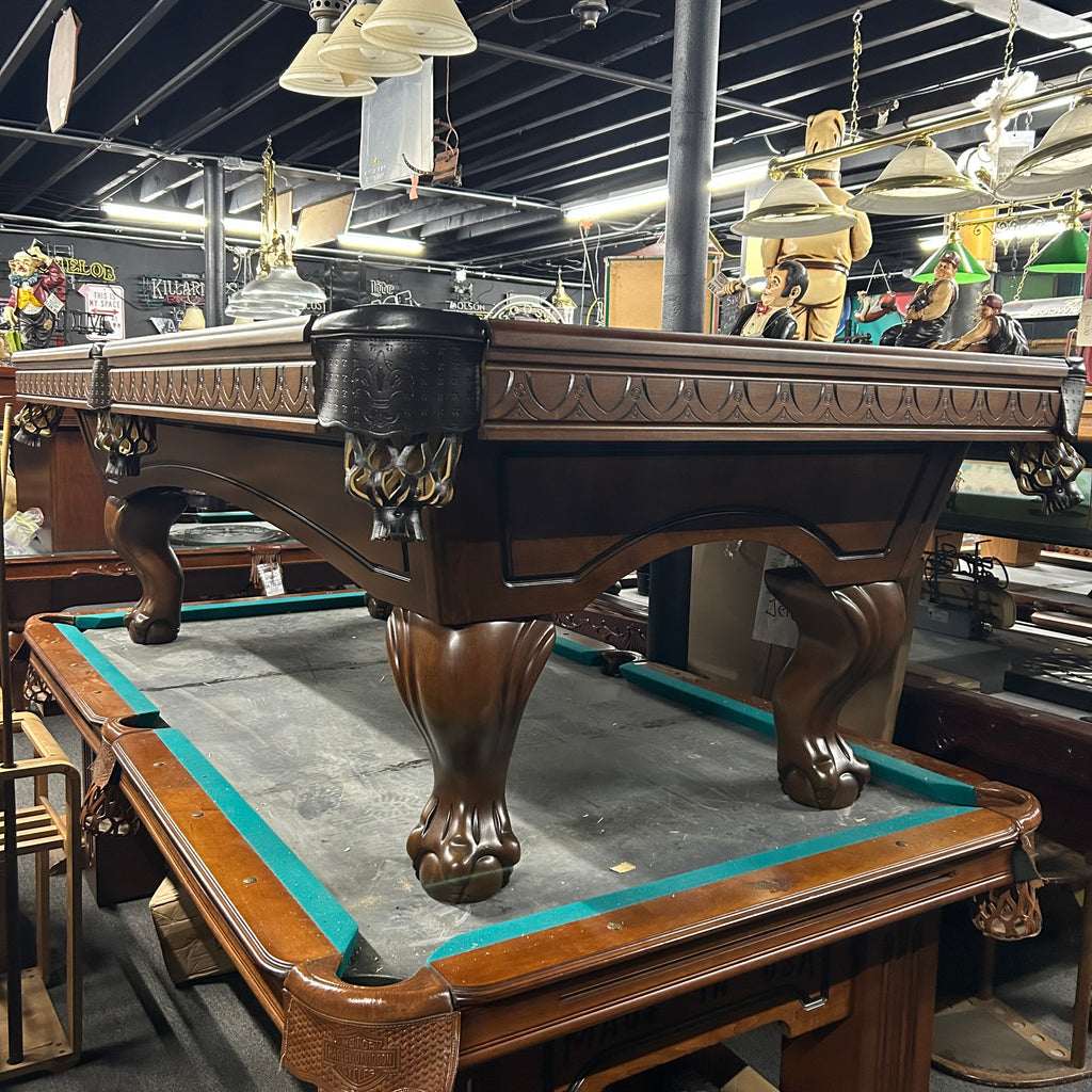 Dark walnut brown pool table with routed aprons and arched cabinet with ball and claw leg