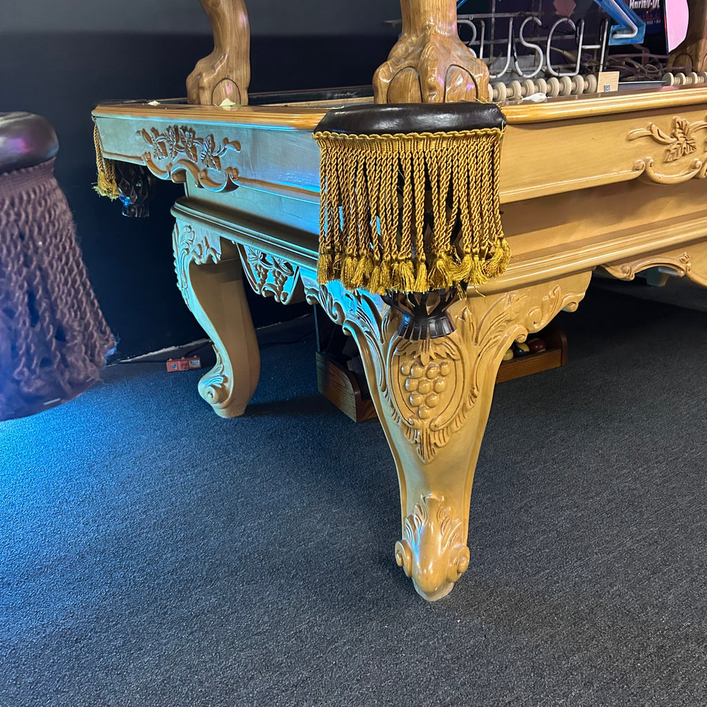 Corner view of pool table with gold fringe pockets and custom ornate rams horn leg wide view