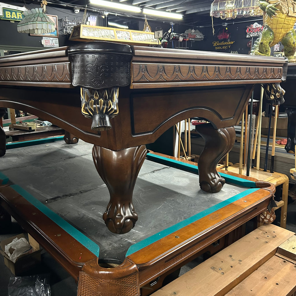 Close up of Dark walnut brown pool table with routed aprons and arched cabinet with ball and claw leg