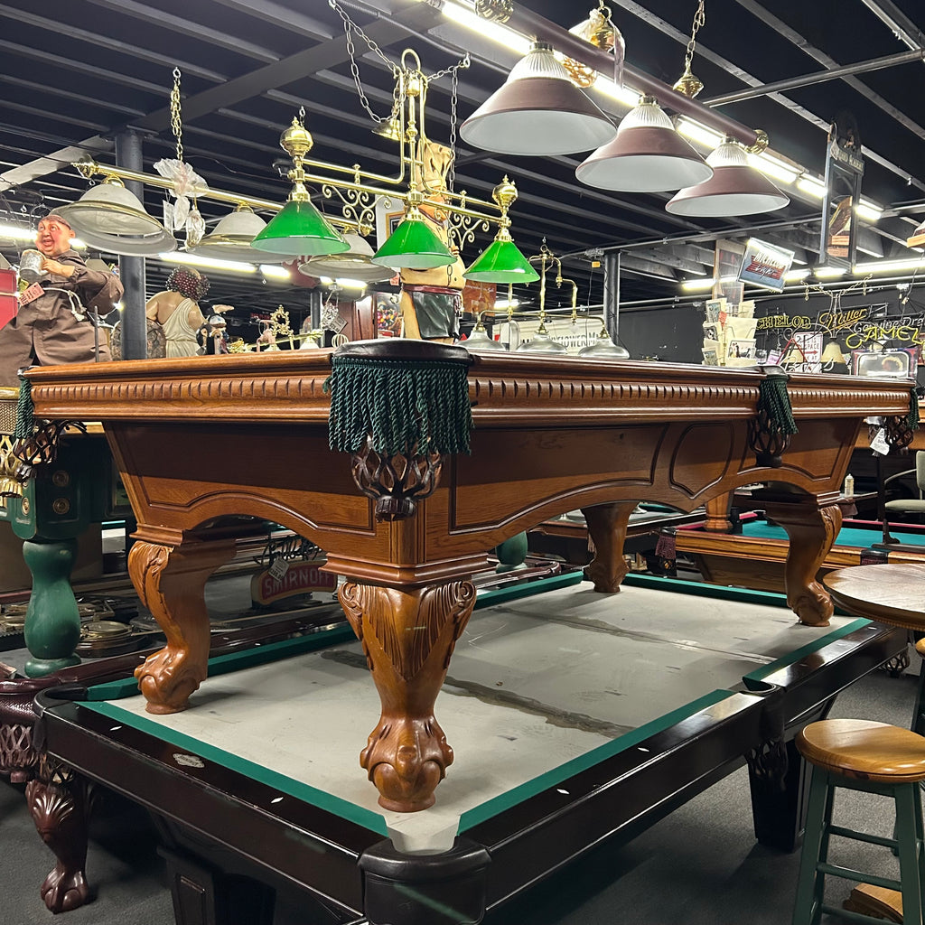 Oak pool table overall from left side with green fringe pocket and ball and claw legs