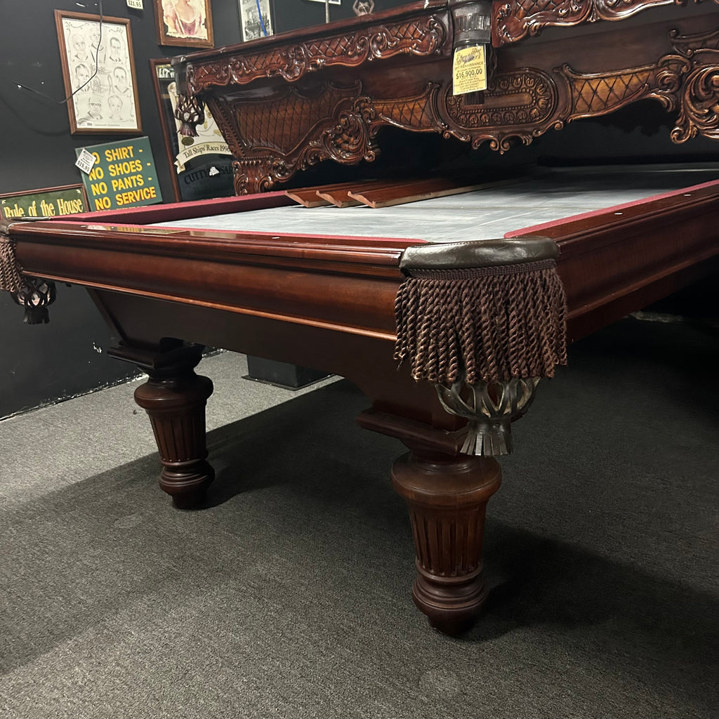 Corner view of pool table in mahogany finish with fringe pocket and round leg from right side