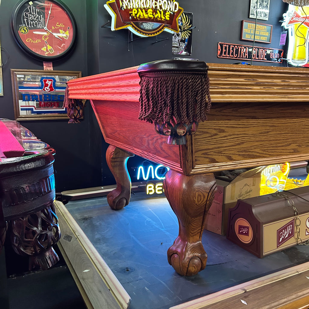 Corner view of Olhausen oak pool table with ball and claw leg and fringe pocket