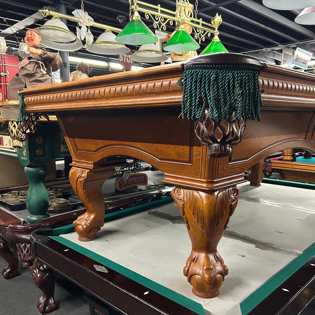 Corner view of pool table with green fringe pocket and oak ball and claw leg