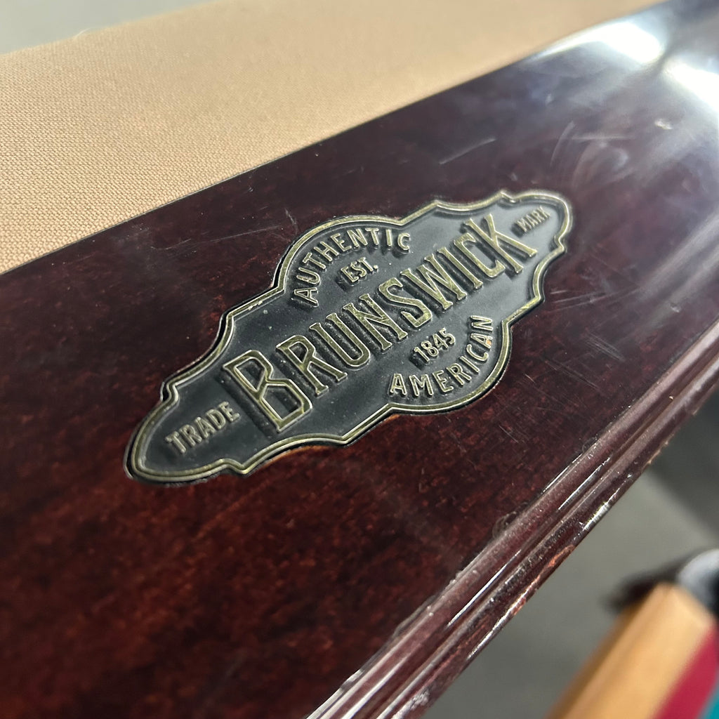 Closeup of faceplate on pool table rail with brunswick authentic american on it