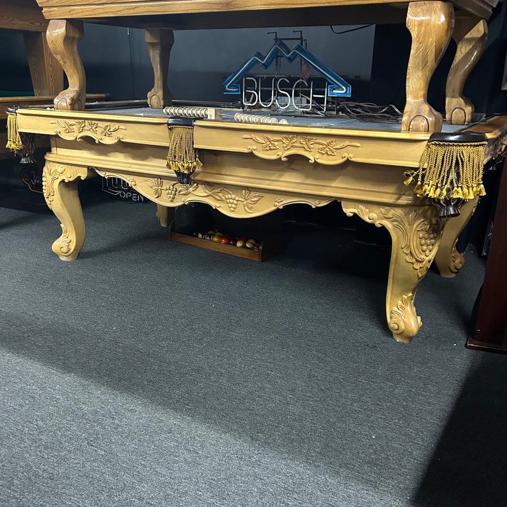 Natural finish pool table with fringe gold pockets and ornate detailing