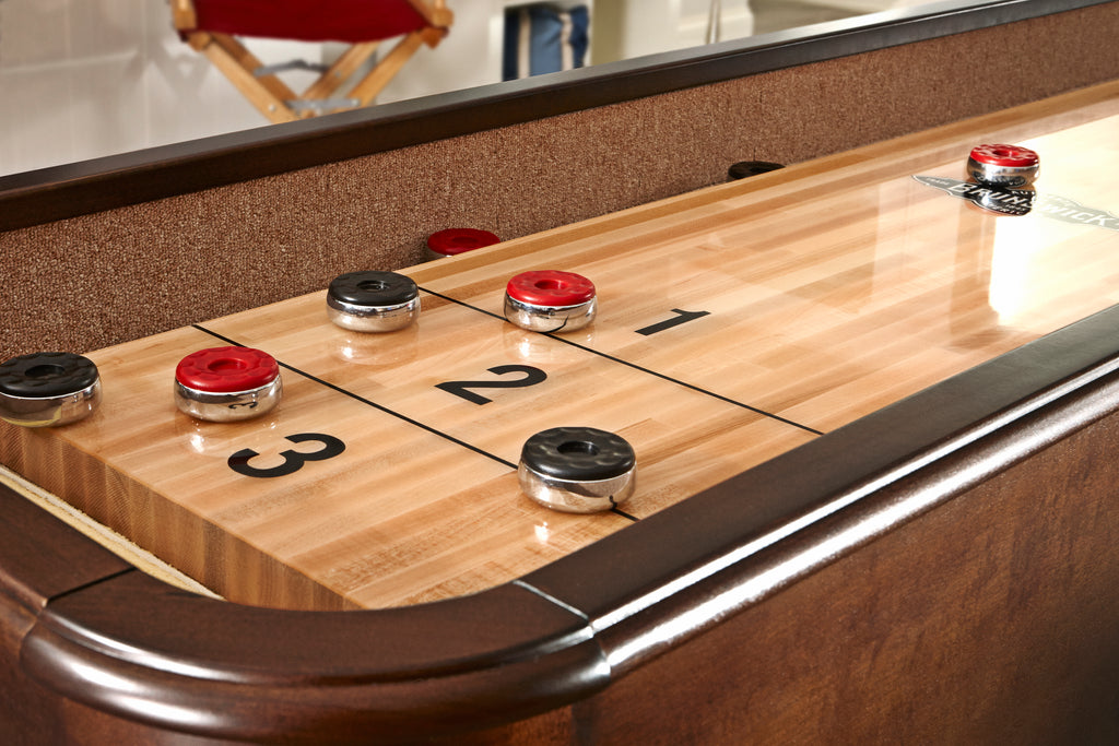 Shuffleboard playfield chestnut finish with red and black pucks on it 