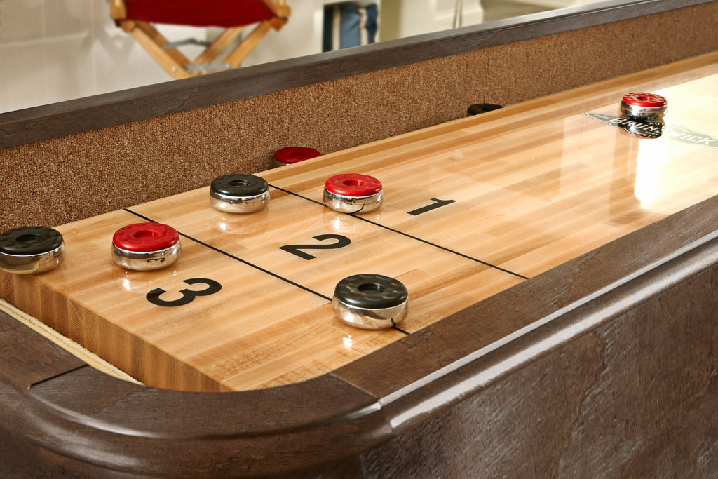 Shuffleboard playfield nutmeg finish with red and black pucks on it
