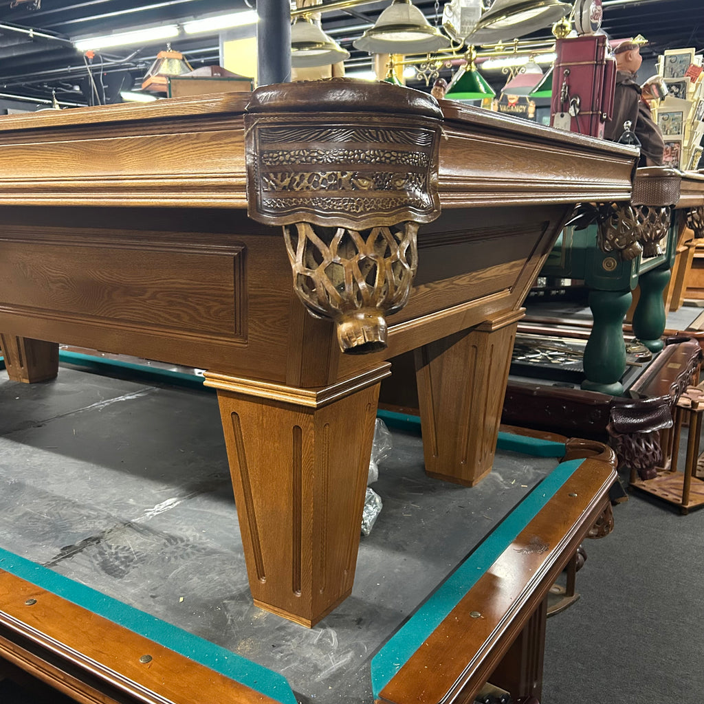 Corner view of pool table with custom leopard shield pocket in oak finish with tapered leg