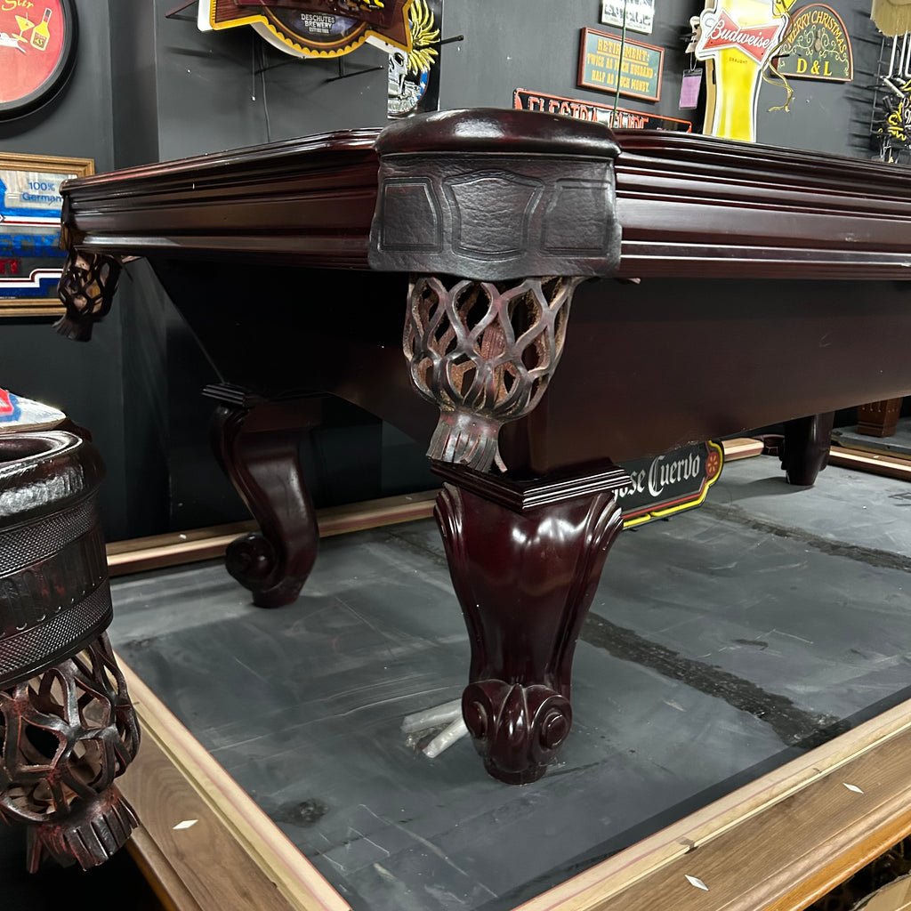 Corner view of mahogany finish pool table with ball and claw leg 