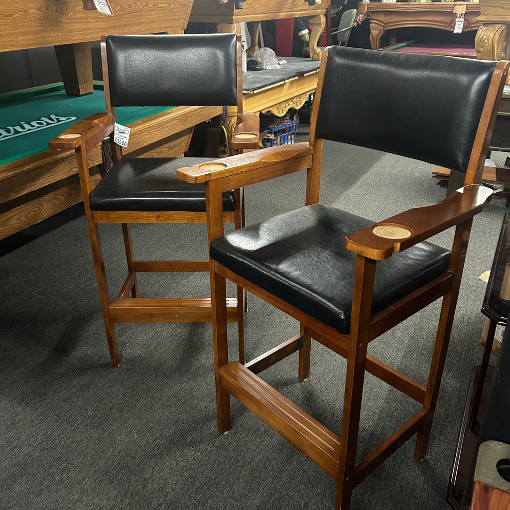 Pair of wooden bar stools with black leather seats in a store setting.