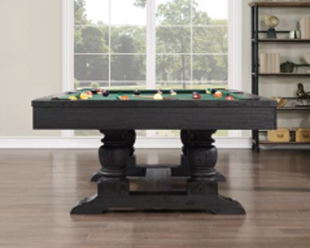 Pool table with green felt and billiard balls in a room with large windows and a bookshelf.