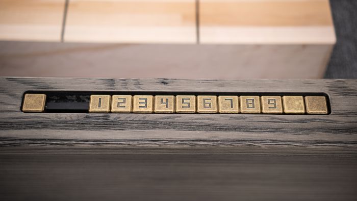 Closeup of scorer on rail with brass numbers 